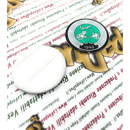 Écusson en résine Ø 53 mm sur base en aluminium. Logo vintage VESPA TECNICA 1946, gris et vert, à appliquer sur les accessoires VESPA à l'aide d'un adhésif. Ø 53 mm