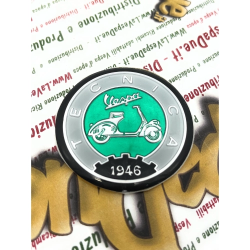 Écusson en résine Ø 53 mm sur base en aluminium. Logo vintage VESPA TECNICA 1946, gris et vert, à appliquer sur les accessoires VESPA à l'aide d'un adhésif. Ø 53 mm