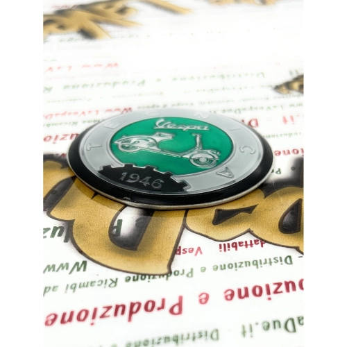 Écusson en résine Ø 53 mm sur base en aluminium. Logo vintage VESPA TECNICA 1946, gris et vert, à appliquer sur les accessoires VESPA à l'aide d'un adhésif. Ø 53 mm