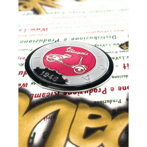 Écusson en résine Ø 53 mm sur base en aluminium. Logo vintage VESPA TECNICA 1946, gris et rose, à appliquer sur les accessoires VESPA à l'aide d'un adhésif. Ø 53 mm